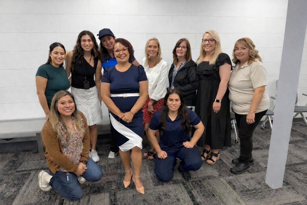 Liz St. James stands with a corporate client team for a group photo after her speech in a meeting room