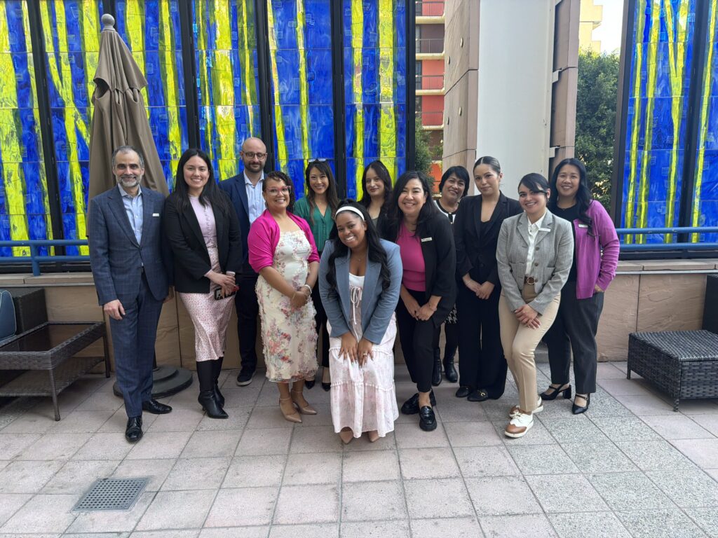 Liz St. James stands with the Omni Los Angeles Hotel team for a group photo on a patio after her speaking engagement.